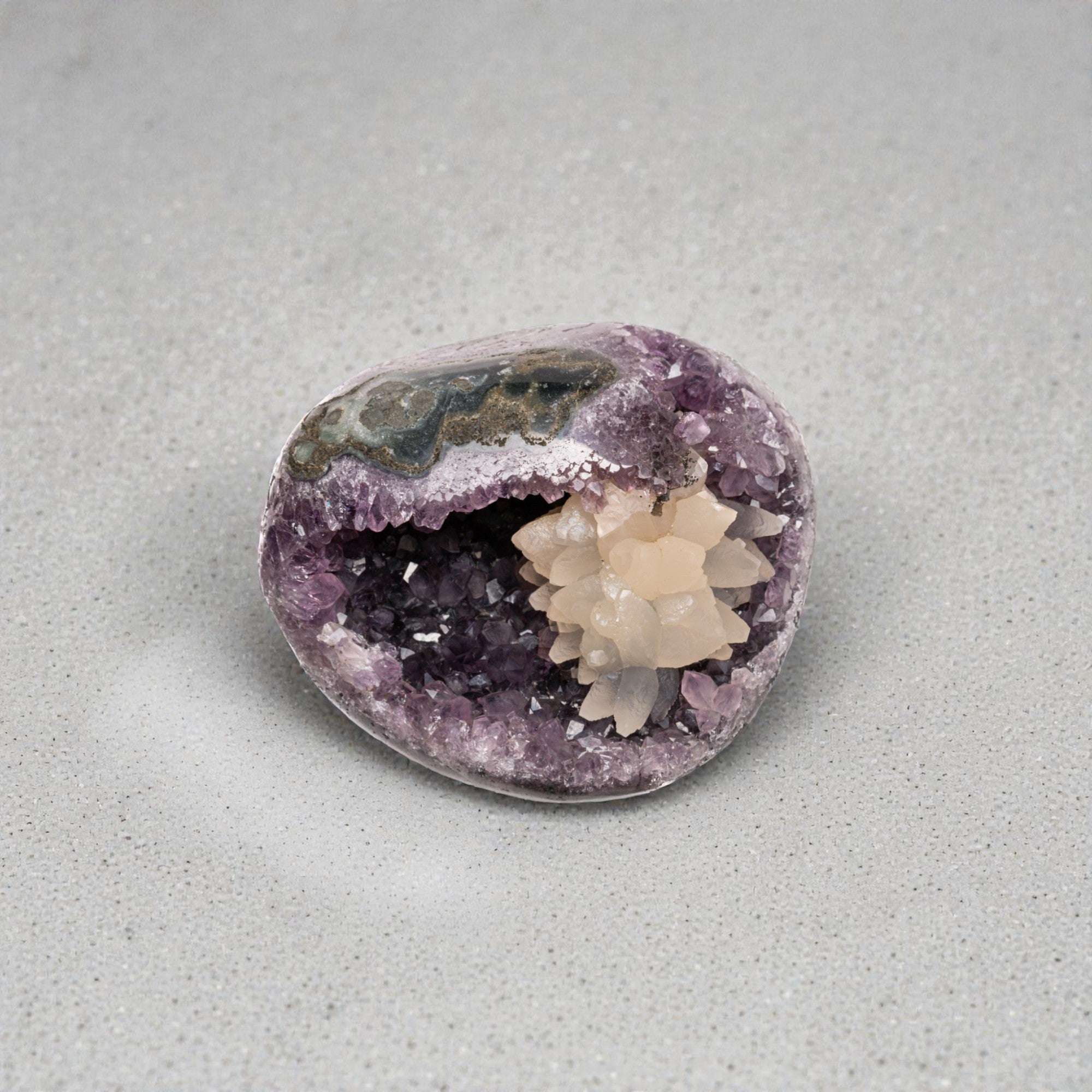 Small amethyst crystal geode with contrasting white calcite formation inside a volcanic quartz cavity, polished into a compact display piece.