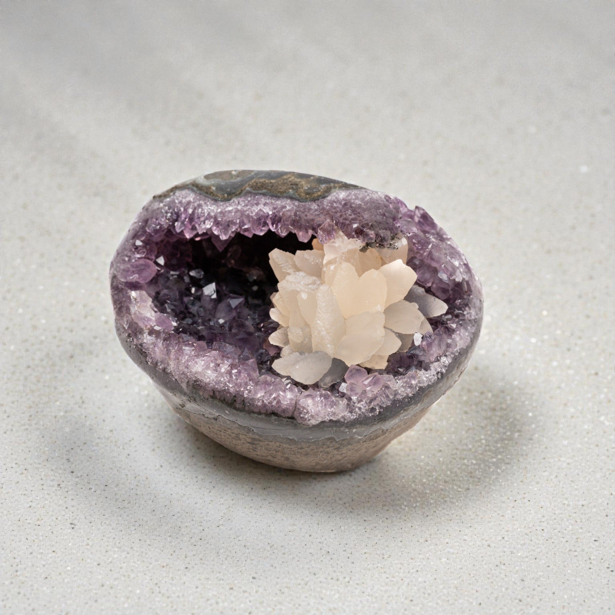 Mini amethyst geode featuring a deep purple druzy quartz interior accented by a white calcite crystal cluster, set within a natural banded agate rim.
