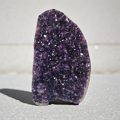 Huge deep violet Uruguayan amethyst cluster standing upright in natural light, featuring dense sparkling crystal points