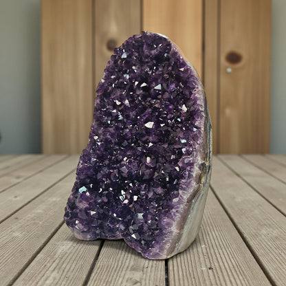 Upright amethyst cluster from Uruguay with rich purple crystals and strong light reflections highlighting its faceted surface.