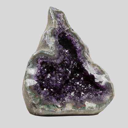 Rich amethyst geode from Uruguay featuring a deep sparkling chamber and swirling quartz textures along the outer shell.
